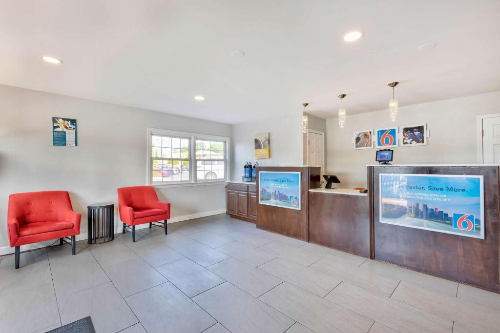 a waiting room with two red chairs and a flat screen tv at Motel 6-Falls Church, VA - Arlington Boulevard in Falls Church