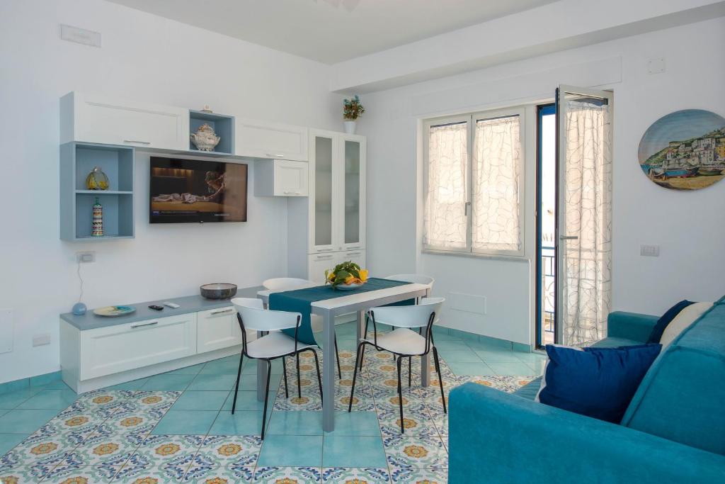 un soggiorno con divano blu, tavolo e sedie di Casa Sammarco a Minori