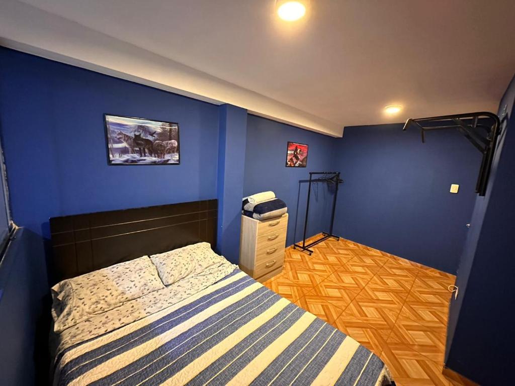 1 dormitorio con cama y pared azul en 300 Departamento Centrico distrito de chorrillos en Lima