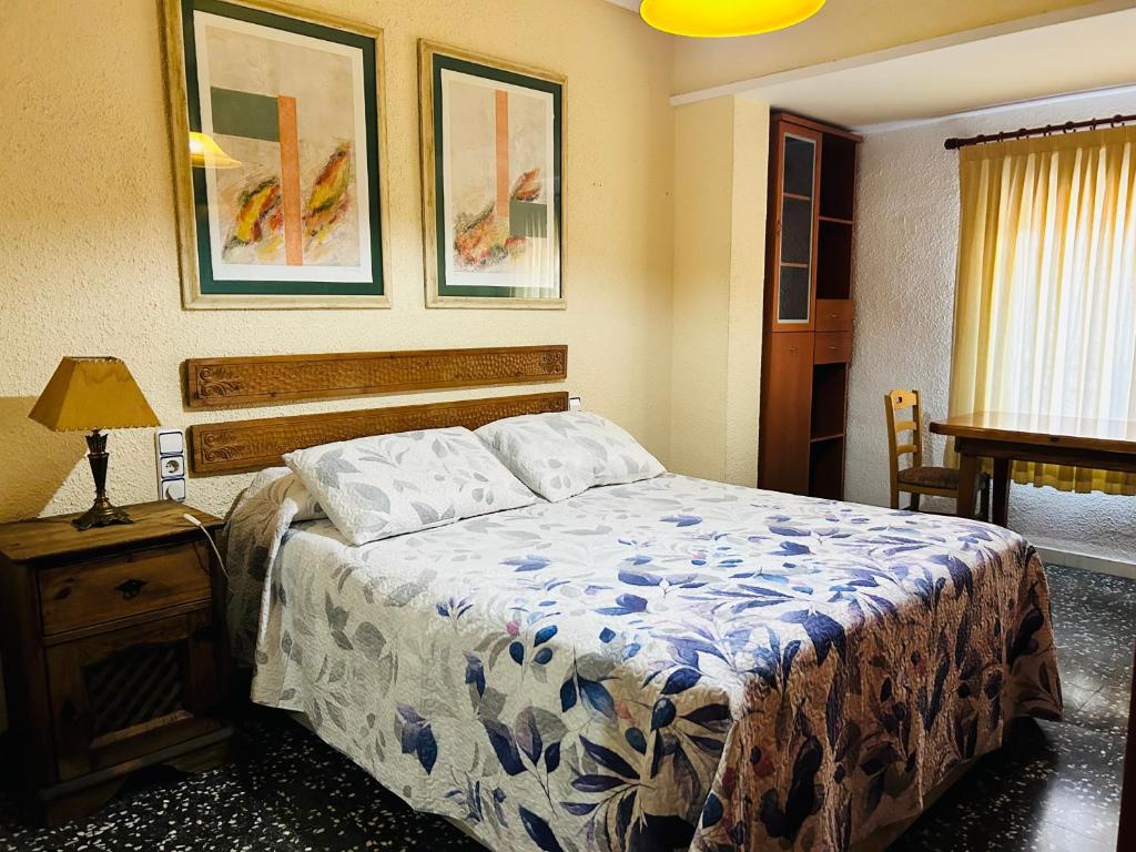 a bedroom with a bed and a table with a lamp at Como en Casa in Valencia