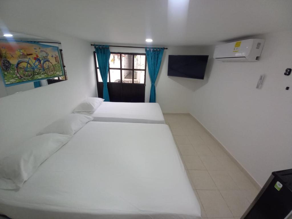 a bedroom with two beds and a window at Hostal Doña Betty in Cartagena de Indias