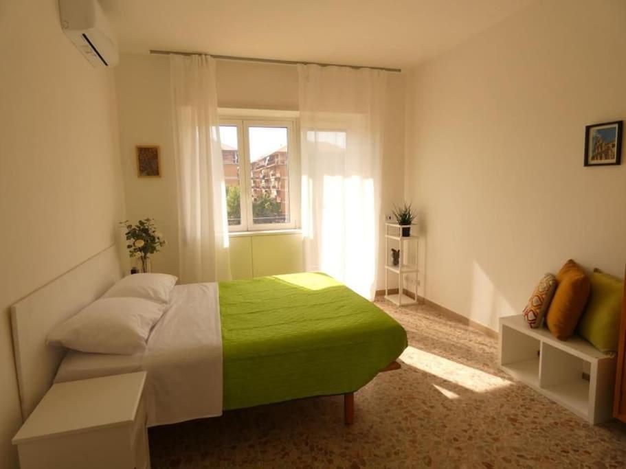a bedroom with a green bed and a window at Casa Cocò - Appartamento al mare in Lido di Ostia