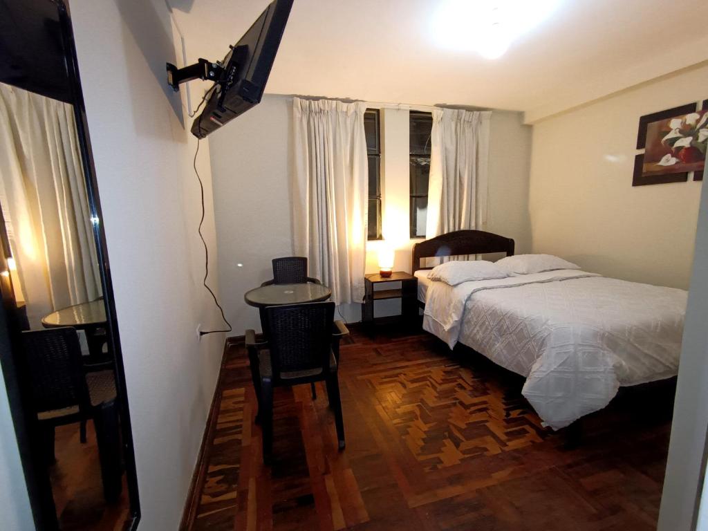 Schlafzimmer mit einem Bett, einem Schreibtisch und einem TV in der Unterkunft Hotel la encantada in Cajamarca