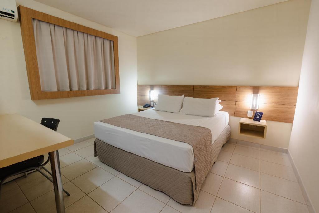 a hotel room with a bed and a desk at Hotel Caiuá Express in Maringá
