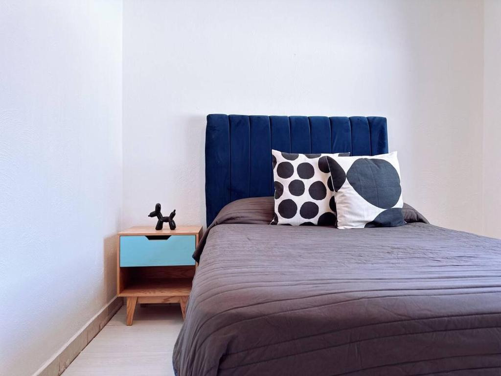 Un dormitorio con una cama azul con almohadas y una mesa en Casa Hotel Estadio Planta Alta, en Guadalajara