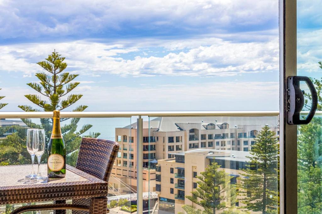 a bottle of wine and a glass on a table on a balcony at Coast on Colley Luxury 1BR Glenelg in Glenelg