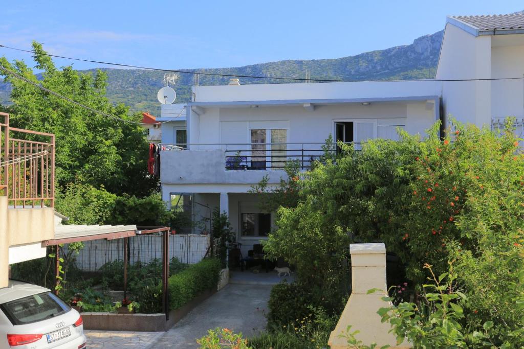 une maison blanche avec une voiture garée devant elle dans l'établissement Apartments by the sea Kastel Kambelovac, Kastela - 20605, à Kaštela
