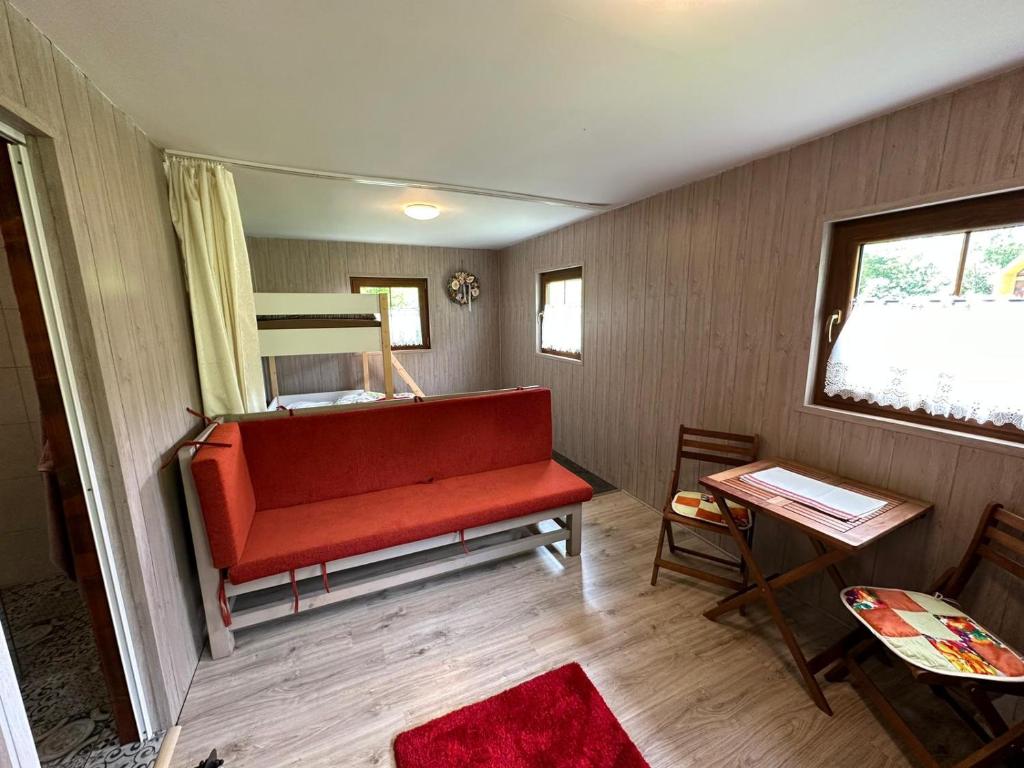 a room with a red couch and a bunk bed at Chatka pod lesom in Banská Štiavnica