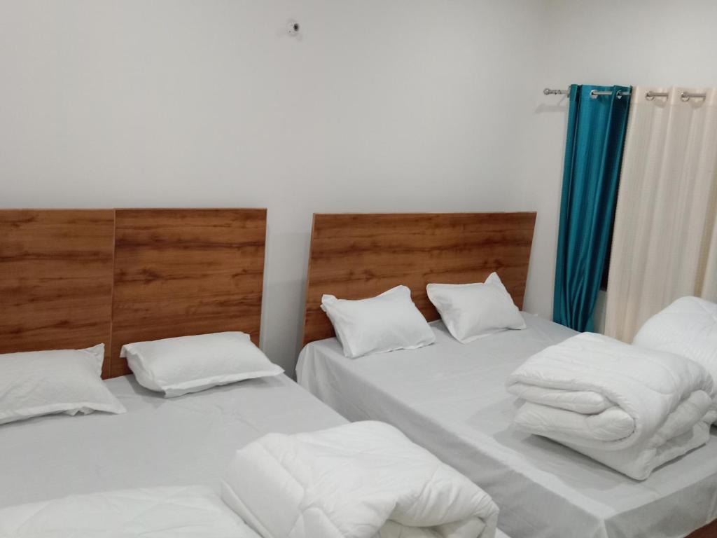 - 2 lits dans une chambre avec des draps blancs et des serviettes dans l'établissement Hotel Arindam, à Phata