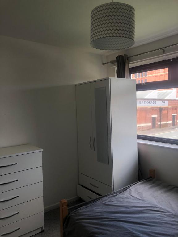 a bedroom with a bed and a cabinet and a window at Falcon drive Room 2 in Oldham