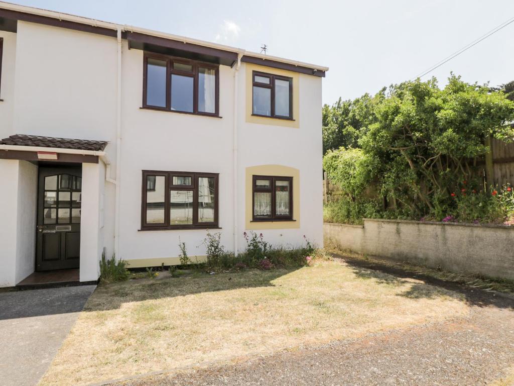 a white house with black windows and a yard at Ocean Breeze in Burnham on Sea