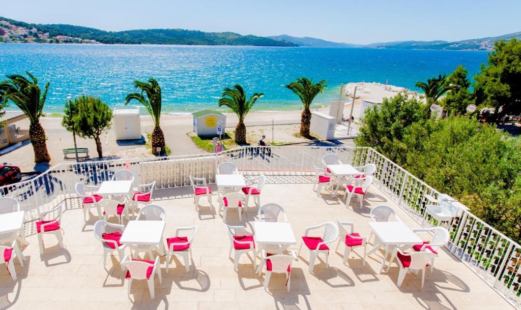 un patio con mesas y sillas y una playa en Apartments Balote, en Trogir