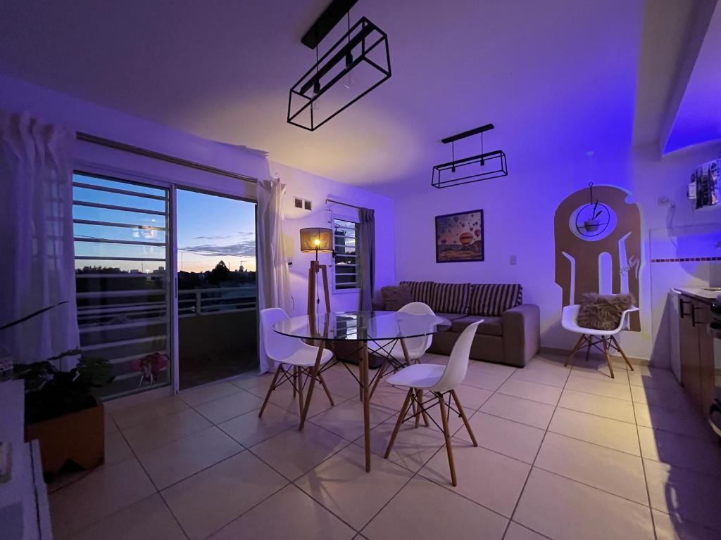 sala de estar con mesa, sillas e iluminación púrpura en Apartamento Alberdi con amplio balcón en Villa María