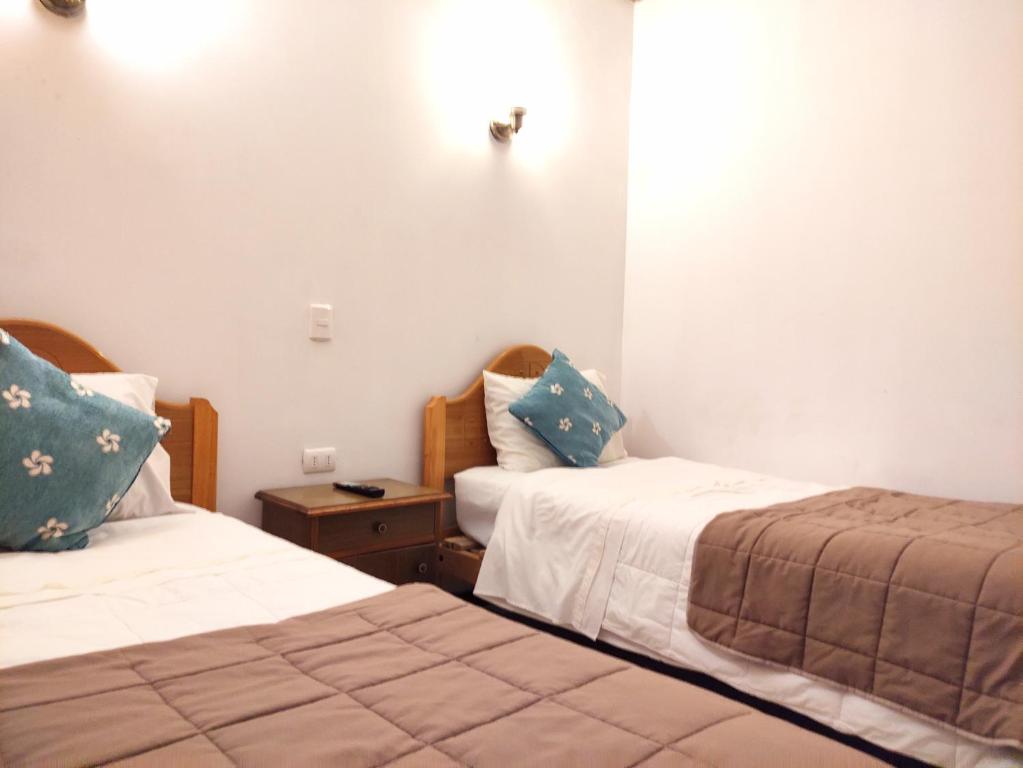 a room with two beds and a night stand with two beds at Hostal valle de la luna in Antofagasta