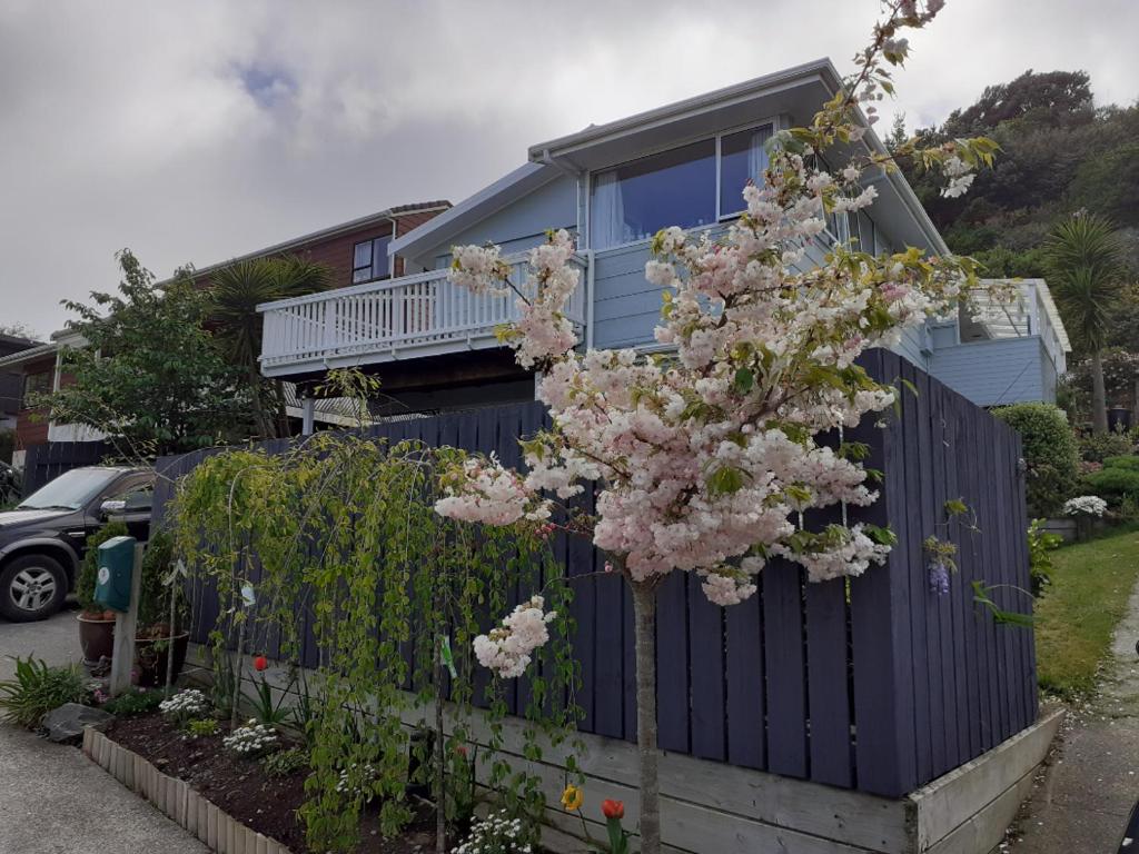 een huis met een bloeiende boom voor een hek bij New, Cosy & Private 1-Bedroom & Living Flat in Porirua