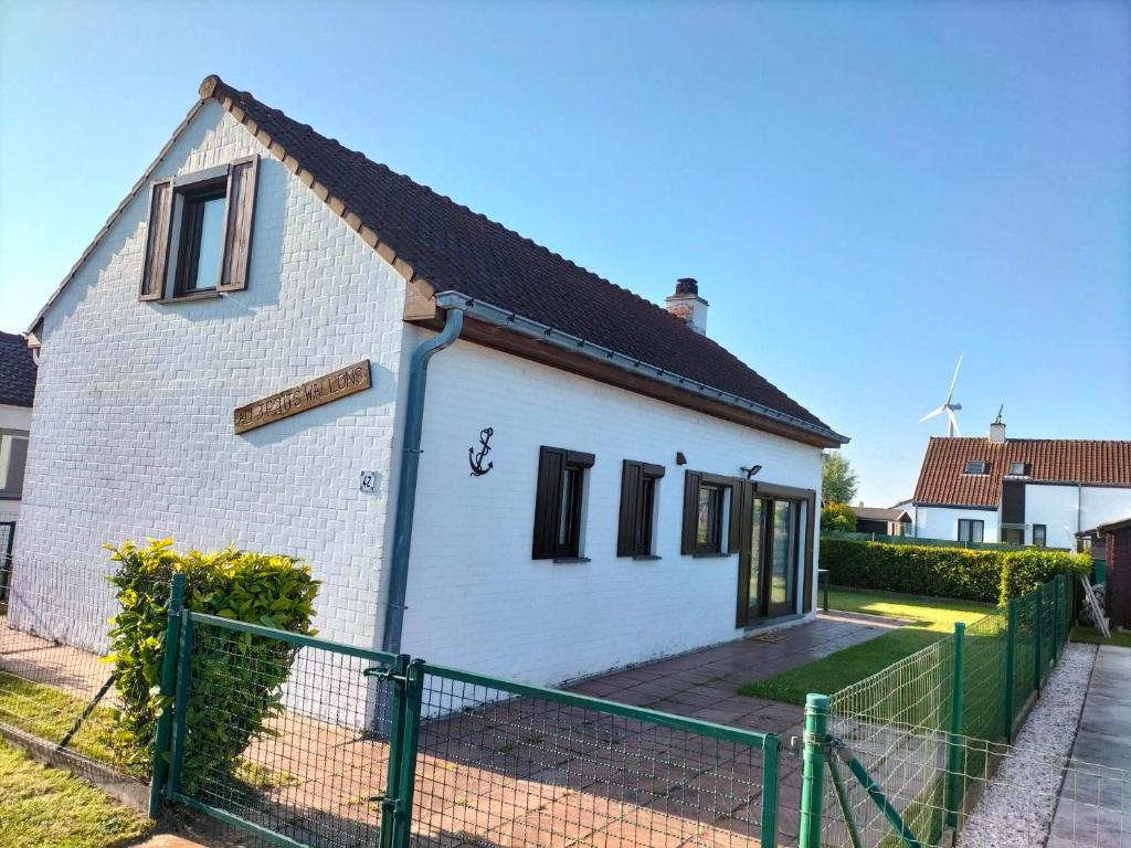 een wit bakstenen huis met een groen hek bij Aux 3 P'tits Wallons in Middelkerke