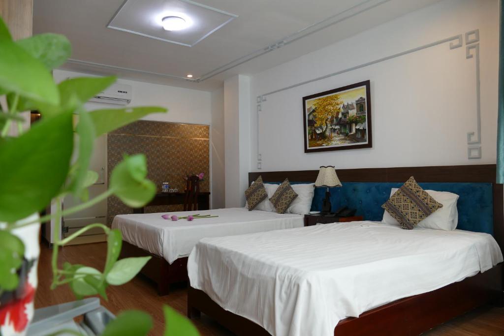 a hotel room with two beds with white sheets at MH Hanoi Hotel in Hanoi