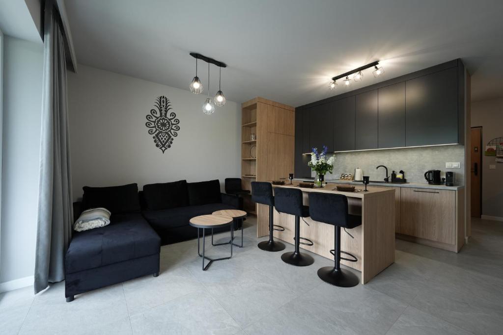 a living room with a couch and a kitchen at Apartament Laguna Beskidów Parzenica z sauną i siłownią - Dream Apart in Zarzecze