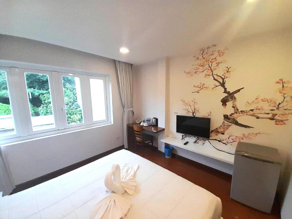 ein Schlafzimmer mit einem Bett mit einem Baumbild an der Wand in der Unterkunft Bayview Hotel & Apartments in Vũng Tàu
