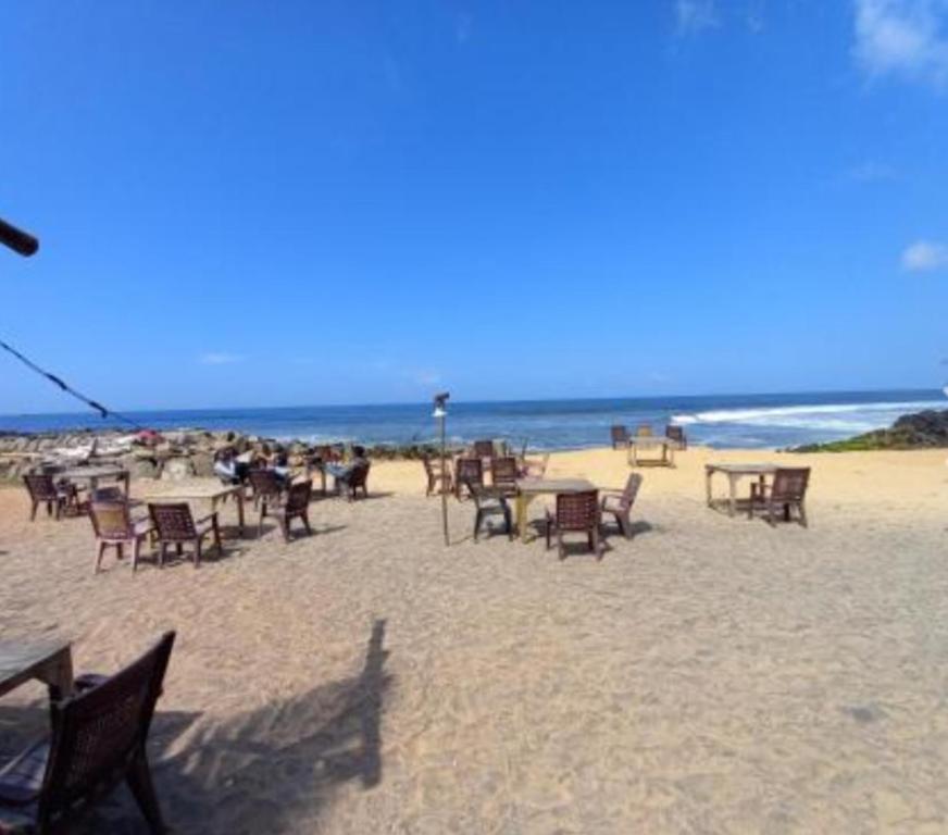 a group of tables and chairs on the beach at East West Beach Resorts in Varkala