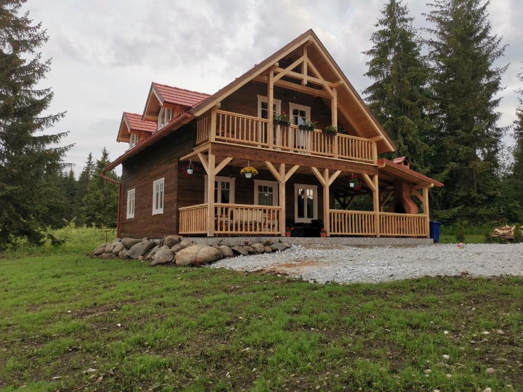 a log home with a large porch and a deck at Cabana Katica 2 vendégház in Borzont