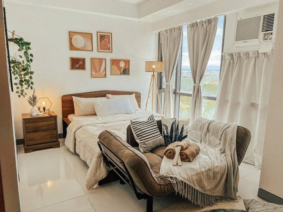 um quarto com uma cama, uma cadeira e uma janela em Chic and Cozy Studio Viceroy Residences Taguig em Manila