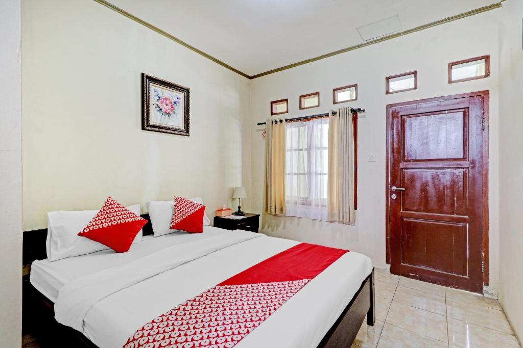 1 dormitorio con 1 cama con almohadas rojas y puerta en Collection O 90461 Graha Atmadja Syariah Guest House, en Bandung