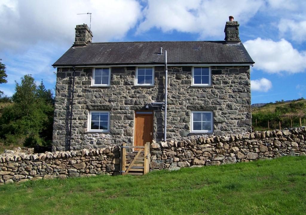 ein altes Steinhaus mit einer Steinmauer in der Unterkunft Llwyniarth in Dolgellau