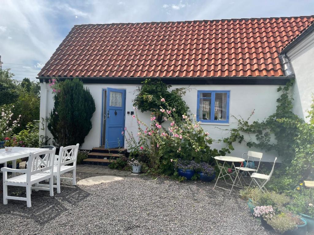 een wit huis met een blauwe deur en een tafel en stoelen bij ØsterLars blue Pearl in Gudhjem