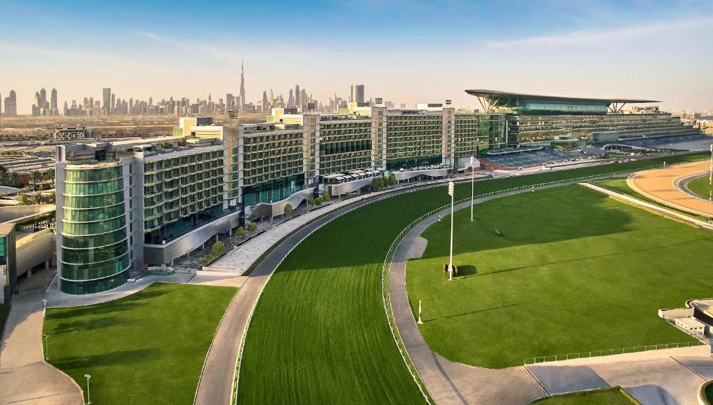 ドバイにあるThe Meydan Hotel Dubaiの市前の緑の芝生がある大きな建物