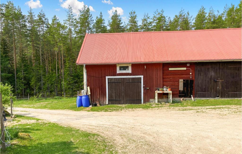 a red barn with a red roof next to a dirt road at Amazing Apartment In Skrblacka With Kitchen in Skärblacka