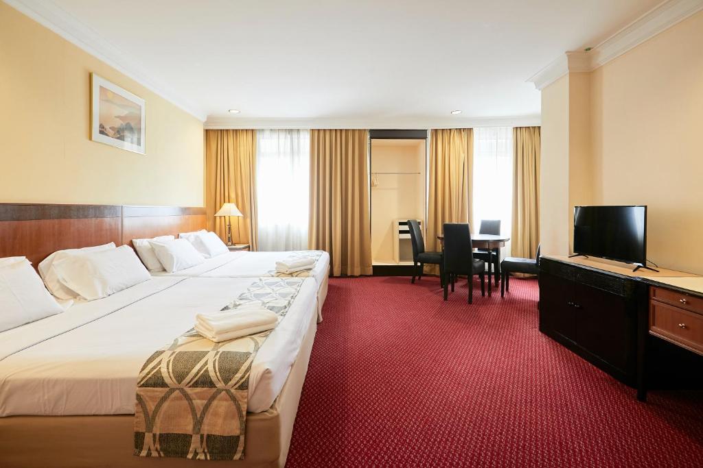 una camera d'albergo con un grande letto e una TV di Grand Pacific Hotel a Kuala Lumpur