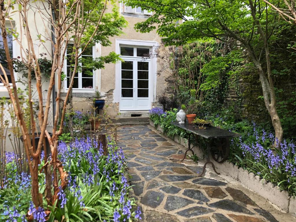 un jardín con flores púrpuras y una puerta blanca en Résidence étoile, en Saint-Yrieix-la-Perche