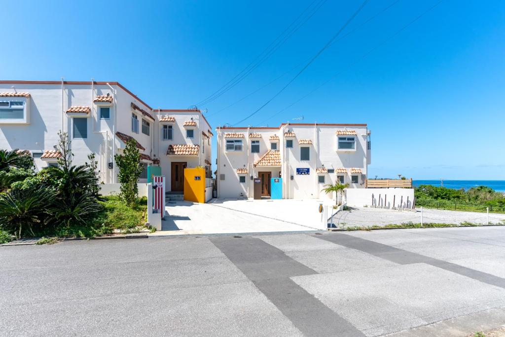 a row of white houses with the ocean in the background at ザ・ヴィラス待遠屋 in Bise