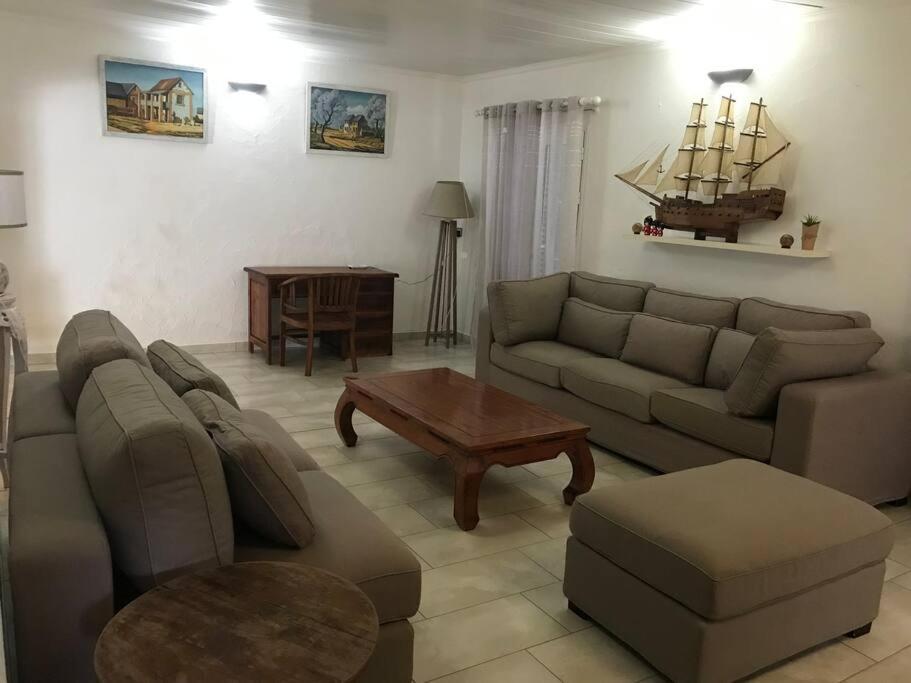 a living room with a couch and a table at Charmante villa située dans l’Est de l’île. in Village Sainte Anne