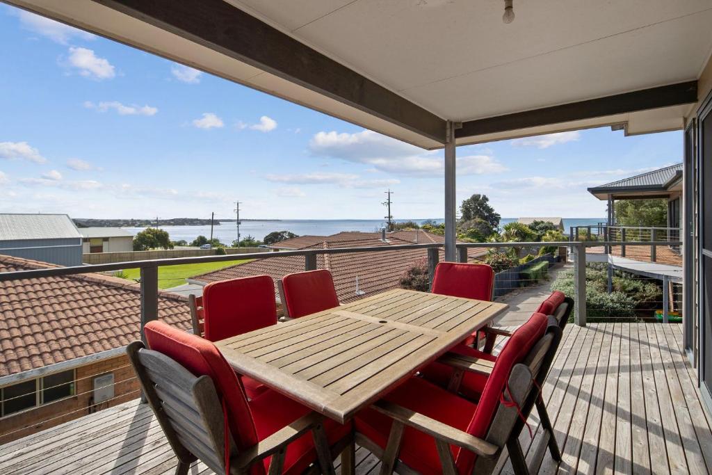 a deck with a wooden table and chairs on a balcony at 3 at 35 Phillip Island Rd in San Remo