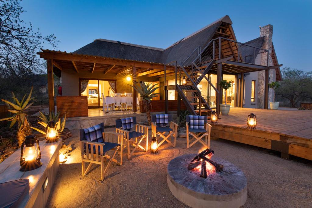a house with a deck with chairs and a fire pit at Ntoma House in Hoedspruit