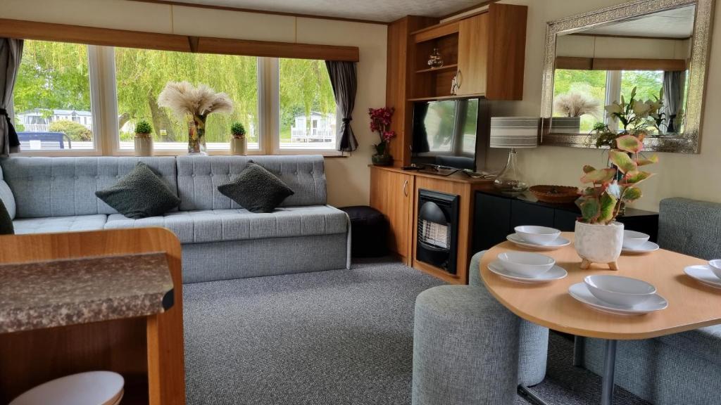 a living room with a couch and a table at 3 Bed Caravan at Parkdean Resort Southview Skegness on a Fishing Lake in Lincolnshire