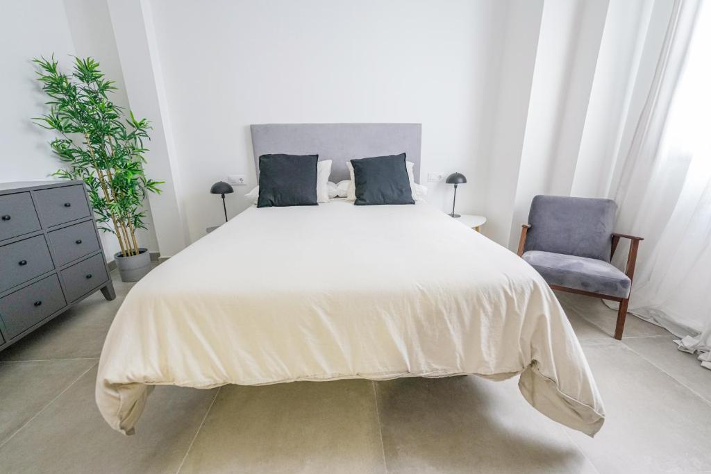 um quarto com uma grande cama branca e uma cadeira azul em Moott Homes Suites Casa de los Leones APTO 1 em Almeria
