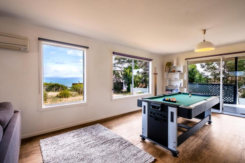 a living room with a pool table and windows at Eagles Rest in Coles Bay