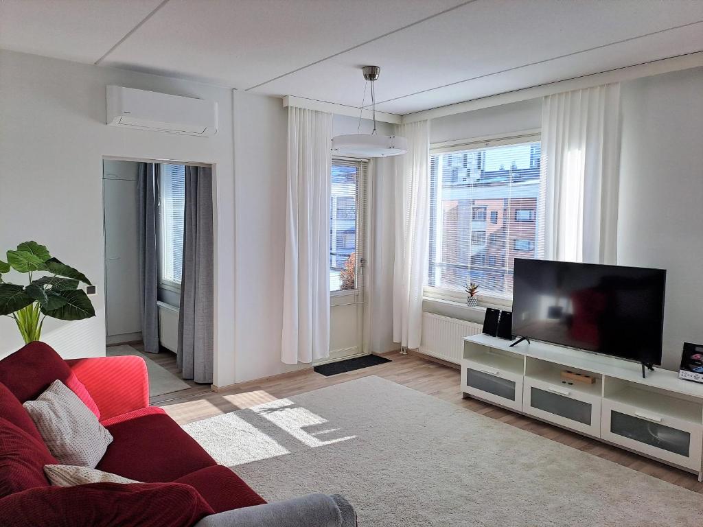 uma sala de estar com um sofá vermelho e uma televisão de ecrã plano em Saunallinen kaksio ilmastoinnilla ja autopaikalla! em Oulu