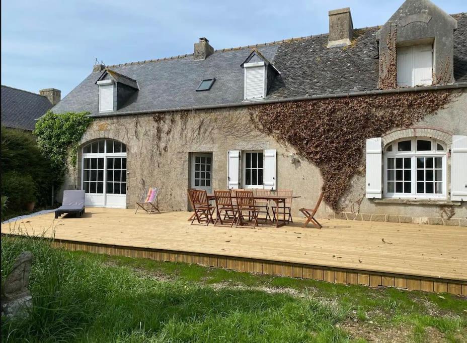 a house with a wooden deck in front of it at Belle longère au calme in Carantec