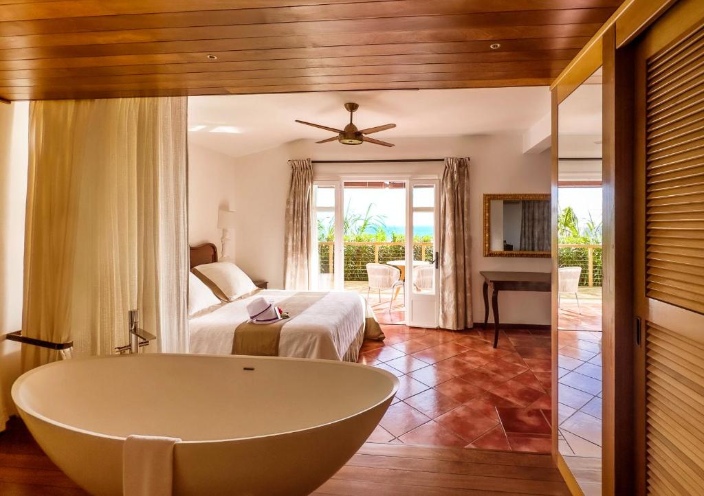 サン・ルにあるBlue Margouillat Seaview Hotel-RELAIS & CHATEAUXのバスルーム(バスタブ付)、ベッドルーム(ベッド付)が備わります。