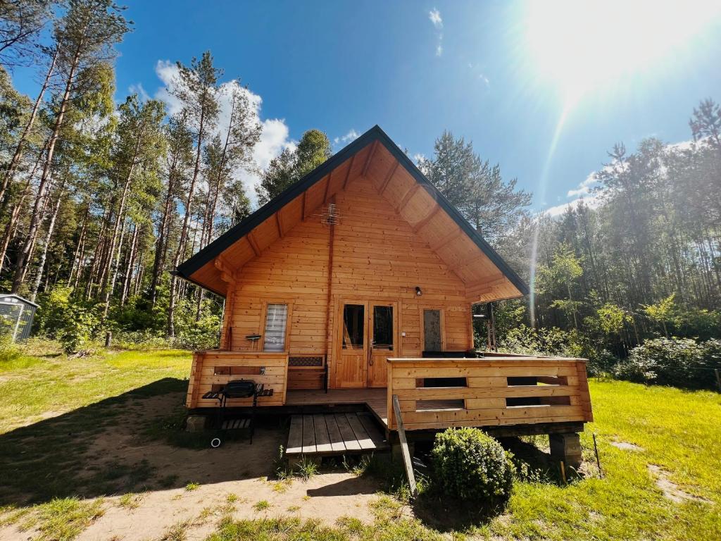 une cabane en rondins dans un champ avec arc-en-ciel dans l'établissement Domek w lesie na Mazurach, à Orzyny