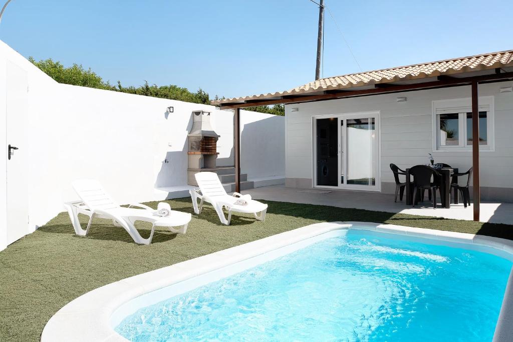 un patio trasero con piscina y sillas y una casa en La Teja 3, en Vejer de la Frontera