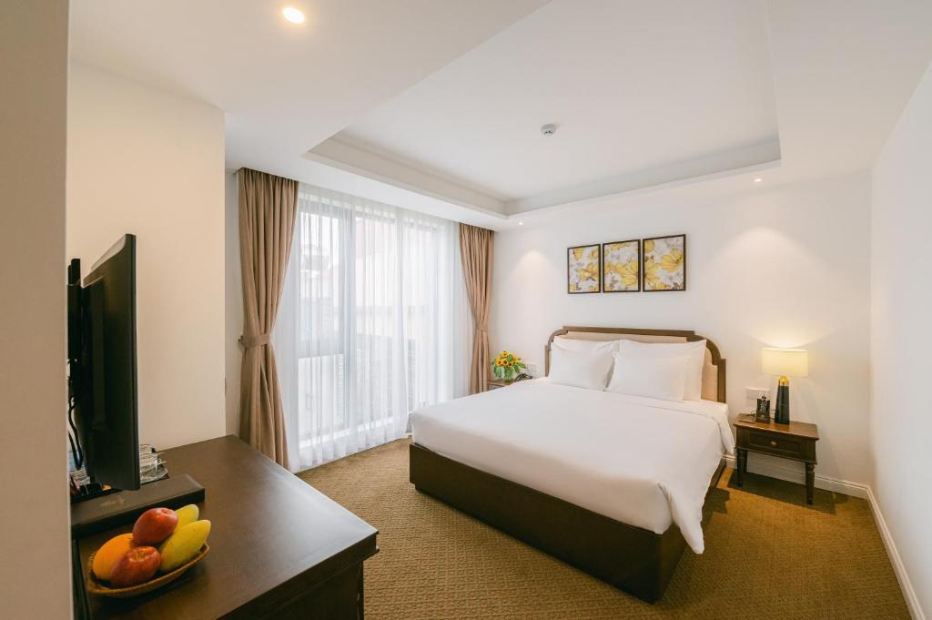 um quarto de hotel com uma cama e uma televisão em Marigold Hotel Hanoi em Hanói