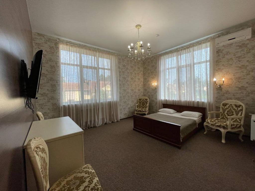 a bedroom with a bed and chairs and windows at Borovik in Novosilki