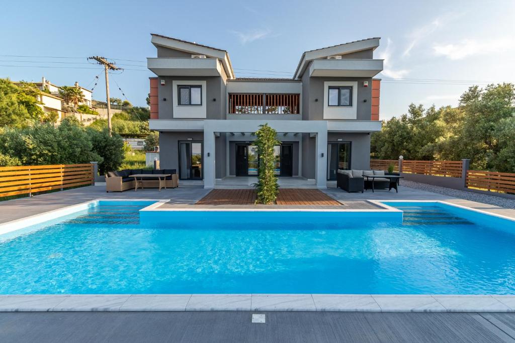 a villa with a swimming pool in front of a house at Assos Luxury Villas in Pefkohori