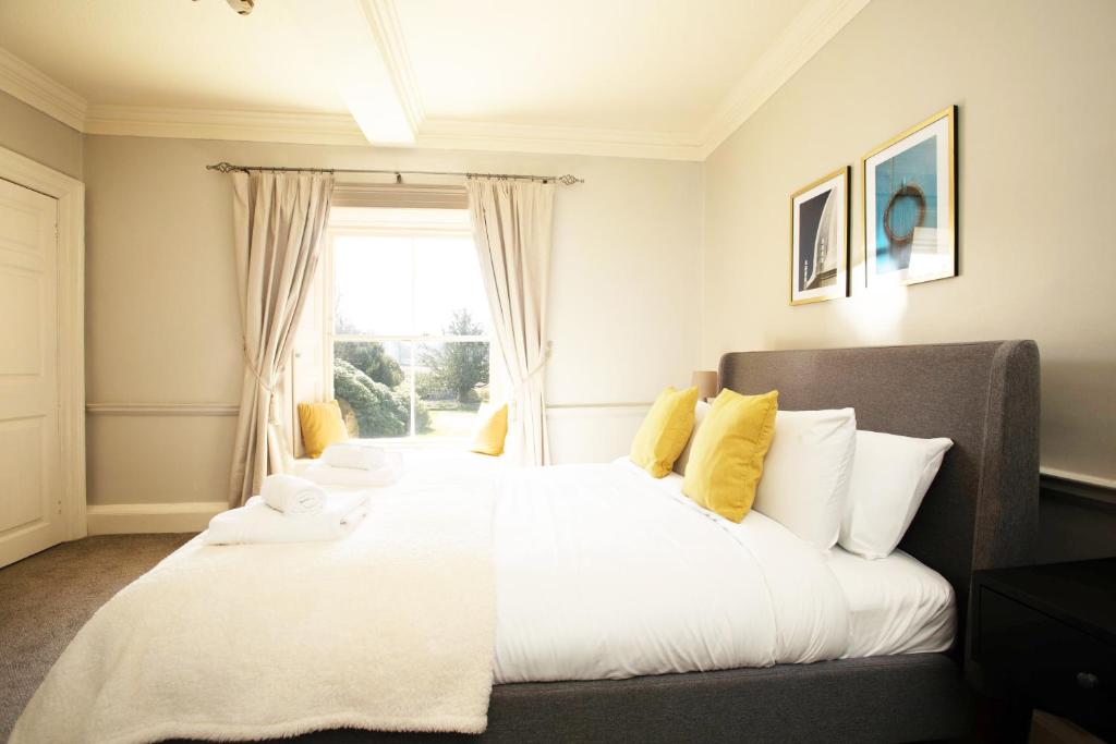 a bedroom with a large white bed with yellow pillows at Lovelady Shield Country House Hotel in Alston