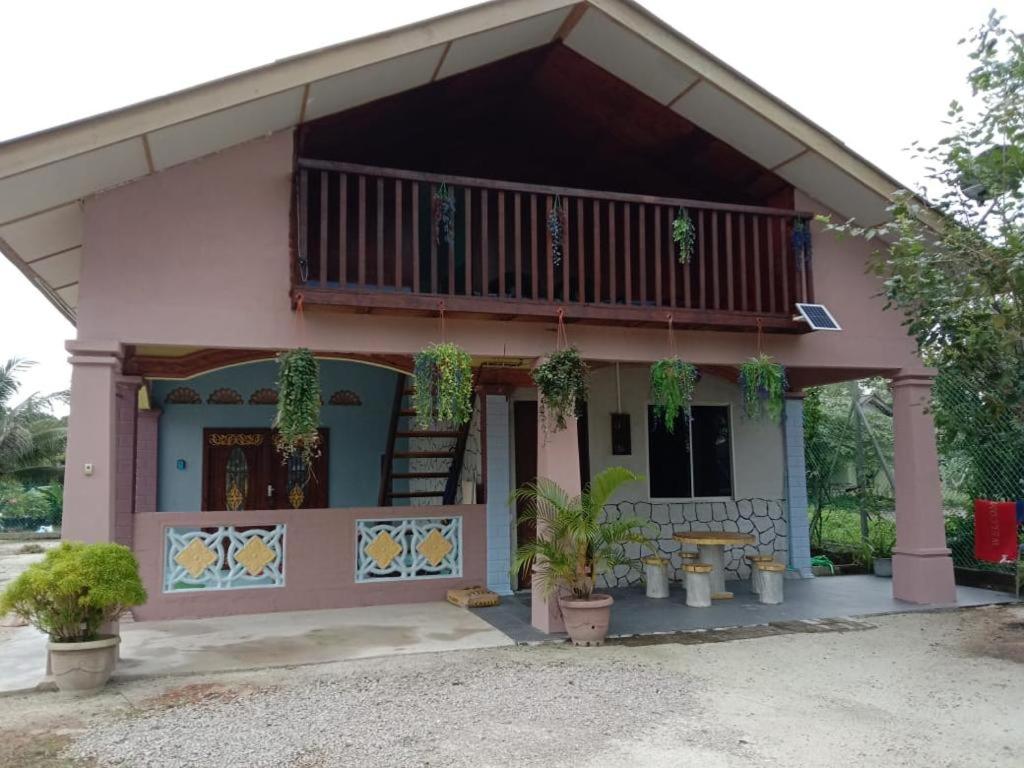 Casa de color rosa con balcón y porche en Homestay D'Hiburan Kuala Rompin, en Kuala Rompin